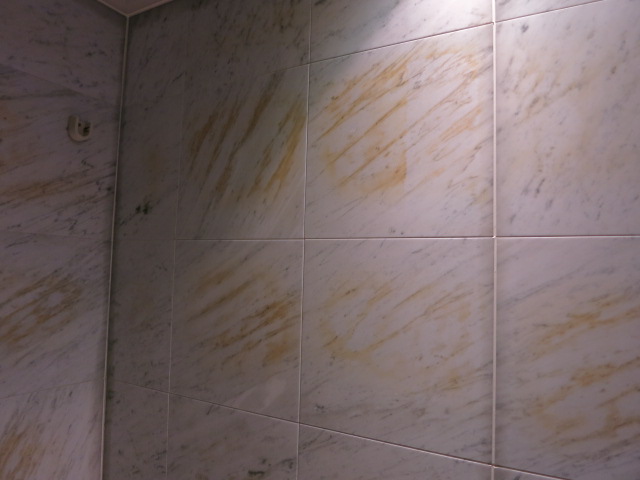 浴室の大理石壁に目立つ茶シミ、サビ抜き施工で白大理石本来の白さ復活