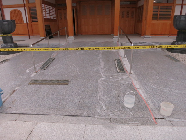 お寺の屋根からの雨水で白御影石バーナー仕上げ床に茶色いシミが